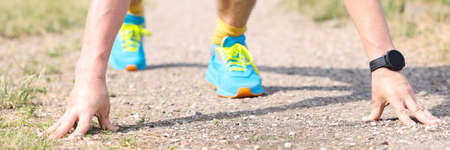 Active man in low starting position prepares for sprint in parkの写真素材
