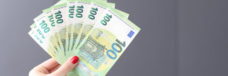 Female hand with red manicure holding lot of euro money banknotes closeup