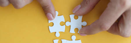 Image of businesswoman connecting elements of white puzzle closeup