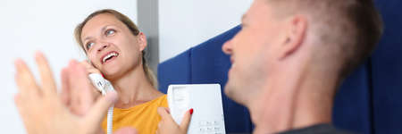 Young woman talking on phone in hotel rooms while lying in bed with man closeup