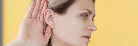 Deaf-mute woman holding her hand near ear