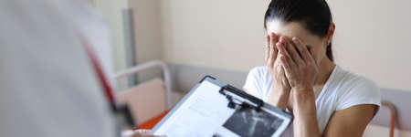 Doctor holding documents in front of crying patient in clinic