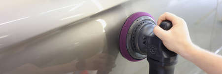 Master polishing car with sander to remove scratches closeup