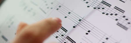 Woman finger points to musical notes. Classical music and music educationの写真素材
