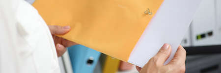 Businesswoman takes out documents from yellow envelope