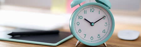 Alarm clock for ten in morning is on desktop in office