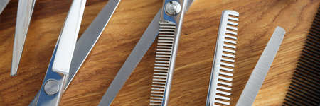 Set of scissors and combs on wooden table closeup