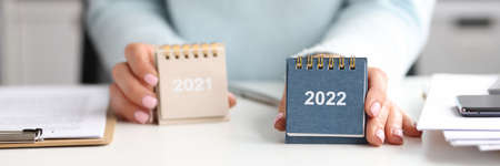 Woman holds calendar for 2021 and 2022 while sitting at desk
