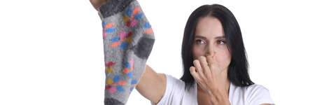 Portrait of young woman covering nose and holding sock in hand closeupの写真素材