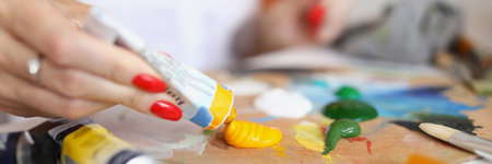 Woman artist squeezes paint for drawing close upの写真素材