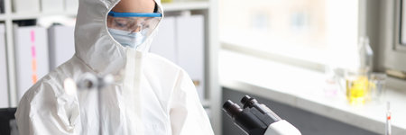 Scientist in protective suit, mask and gloves conducts laboratory researchの写真素材