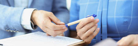 Woman hands pen to partner to sign on document closeupの写真素材