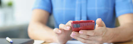 Modern smartphone in female hands and business graphics in workplaceの写真素材