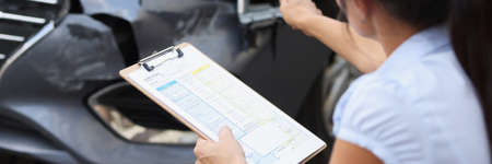 Insurance agent records damage to car after accidentの写真素材