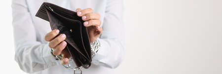 Woman holding empty purse hands tied with chain