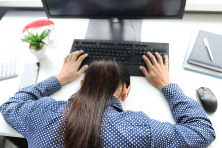 Overworked tired female freelancer or remote worker sleep lying on deskの写真素材
