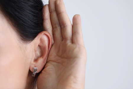 Woman held hand to ear and listened attentively.の写真素材