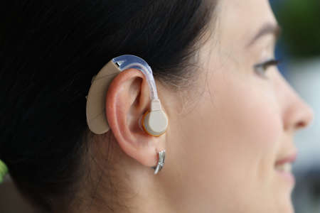Hearing aid is on woman ear closeup