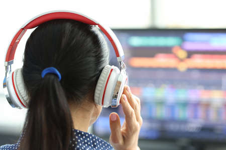 Woman in headphones in front of computer monitorの写真素材