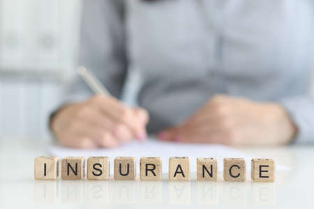 Insurance agent fills out insurance form in office closeupの写真素材