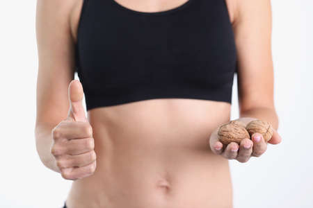 Sports woman holding walnuts and thumbs up