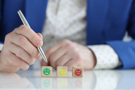 Man in business suit choosing assessment on scale of emoticons closeup