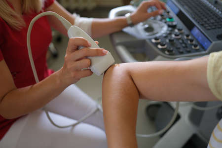 Doctor making ultrasound of patient elbow joint in clinic closeup