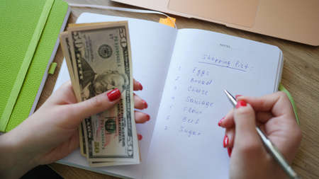 Woman makes shopping list and holds money
