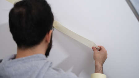 Home repair service master uses masking tape before paintingの写真素材