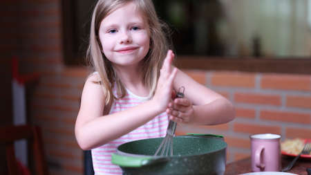 Little smiling girl prepares food in kitchenの写真素材