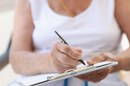Hands of old woman with sheet for writing textの写真素材