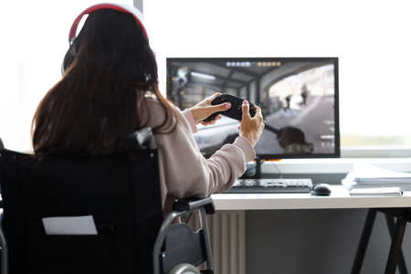 Woman in wheelchair having fun playing computer games