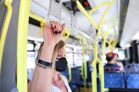 Hand of tourist passenger in protective mask holding handrails in busの写真素材