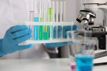 Scientist is holding test tubes with blue green liquids in laboratory