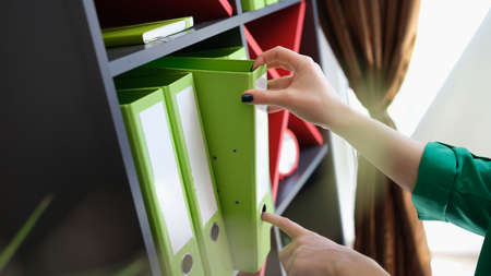 Female hands taking off green folder with documentsの写真素材