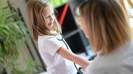 Happy little child using medical stethoscope at doctor appointmentの写真素材