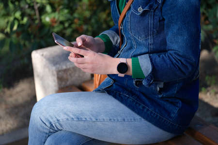 Woman relaxing in park and surfing internet on modern smartphoneの写真素材