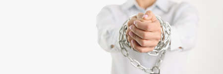 Womens hands are shackled with a large chain, close-up