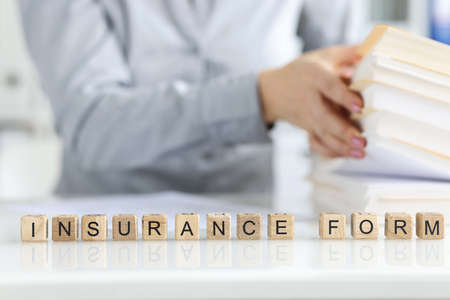Woman working with insurance claim form, word collected of wooden cubesの写真素材