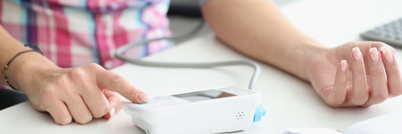 Woman measuring blood pressure with electric digital tonometer closeup