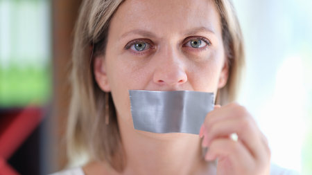 Beautiful woman with duct tape on mouth closeupの写真素材