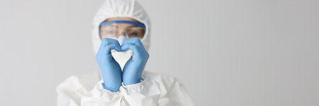 Doctor in protective suit makes heart gesture with hands