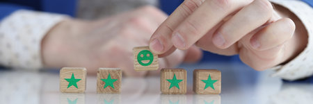 Client is holding smiling smiley face on wooden cube
