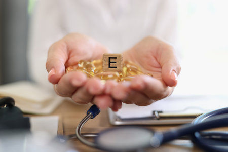 Female practitioner holding capsules and cube with letter Eの写真素材