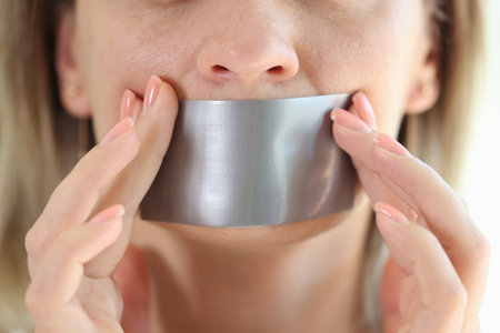 Young woman with duct tape sealed on mouthの写真素材