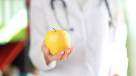 Doctor holding ripe yellow apple in handの写真素材