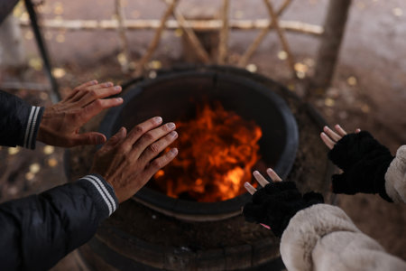Cropped shot of female and male tourists warming hands near bonfire.
