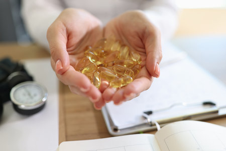 Nutritionist holding heap of vitamin capsules above his desk in medical clinic.の写真素材