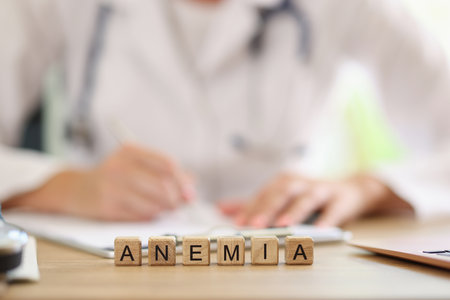 Inscription ANEMIA on wooden cubes and doctor checking medical tests in background.の写真素材