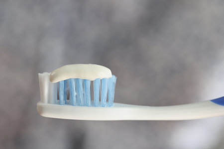 Toothbrush and toothpaste close up on gray blurred background.